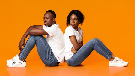 Upset african lady looking at her sad boyfriend, orange backgroundの写真素材