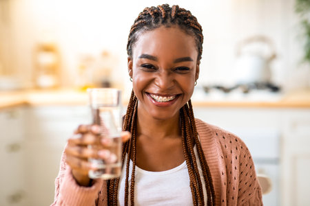 Joyful Black Lady Holding Glass With Water, Offering Refreshing Drink To Camera