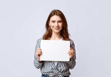 Portrait of beautiful woman holding white blank advertising boardの写真素材