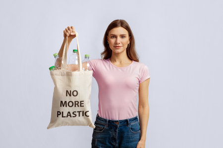 Young Smiling Woman Carrying Eco Tote Bag With No More Plastic Inscriptionの写真素材