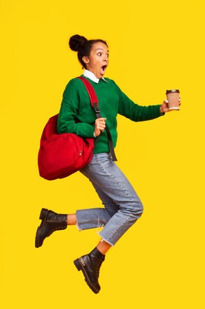 Funny black girl jumping over yellow studio background