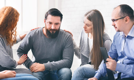 Group supporting depressed man with alcoholism problemの写真素材