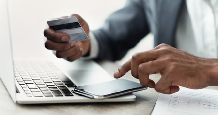 African businessman booking tickets online using smartphone, holding credit card.の写真素材