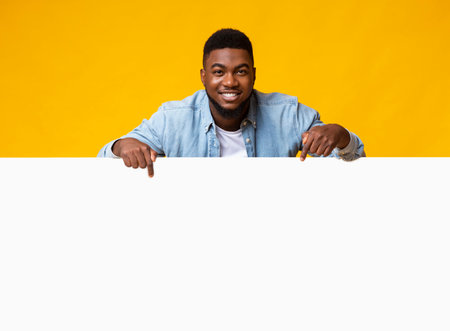 Black man leaning on white board and pointing on itの写真素材