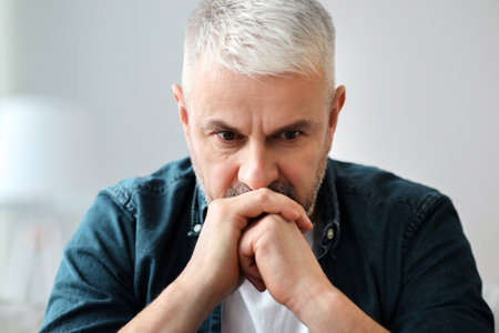 Pensive senior man sitting on couch at homeの写真素材