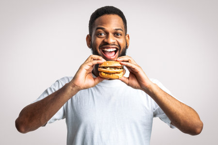 African Guy Biting Burger Eating Unhealthy Junk Food, White Background