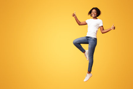 Carefree african-american lady jumping and showing thumb upの写真素材