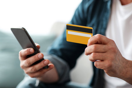 Unrecognizable man with smartphone holding credit card