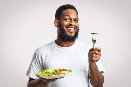 Smiling African American Guy Posing With Vegetable Salad, White Backgroundの写真素材