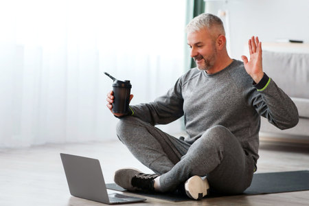 Cheerful old man having online lesson with trainer, using laptopの写真素材