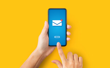 Online correspondence. Top view of young lady pressing READ button on cellphone with incoming email, orange backgroundの写真素材