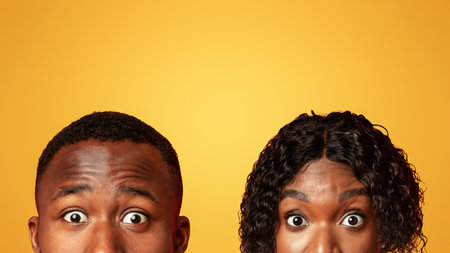 Shocked black couple with big eyes hiding from someoneの写真素材