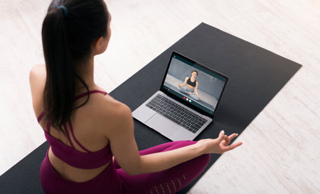Sportive woman having yoga class online, using laptopの写真素材
