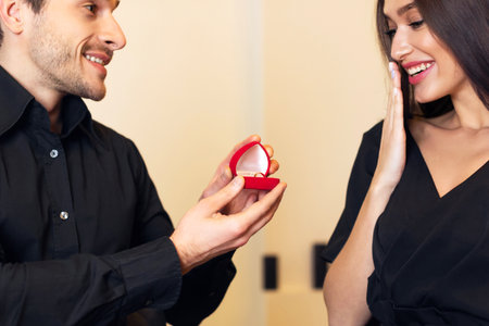 Smiling man making proposal with ring to his fianceの写真素材