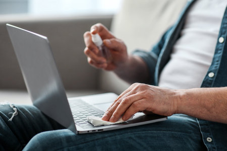 Male hands using disinfectant spray for cleaning laptop, closeupの写真素材