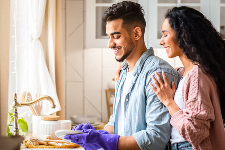 Loving Middle Eastern Husband Helping Wife With Washing Dishes After Lunchの写真素材