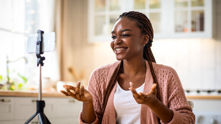 Black Female Blogger Recording Video In Kitchen With Smartphone On Tripod