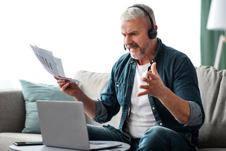 Furious senior businessman having video call with assistantの写真素材