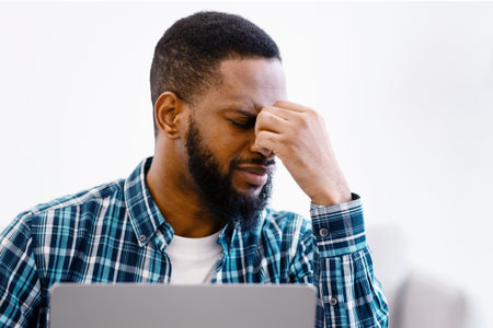 Black Guy Massaging Tired Eyes After Work On Laptop Indoor