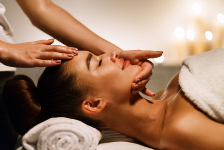 Woman enjoying anti aging facial massage in atmospheric spaの写真素材