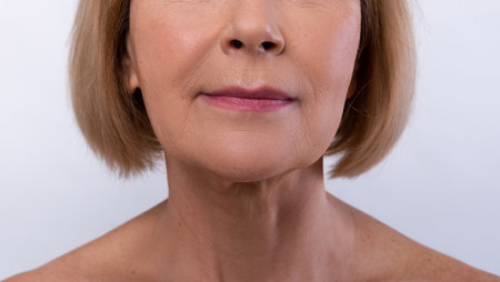 Cropped view of senior woman with silky skin on light studio background, closeup of lipsの写真素材