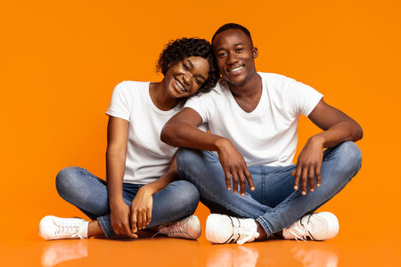 Beautiful african american couple sitting on floor and huggingの写真素材