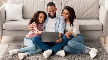 Happy black family using laptop sitting on the floorの写真素材