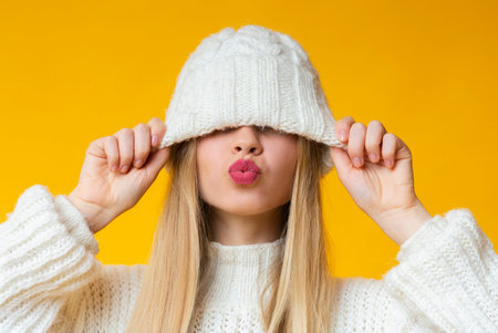 Woman with kissing lips pulling down woollen hatの写真素材