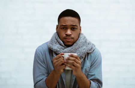 Sick Black Guy Having Chills Standing Over White Wallの写真素材