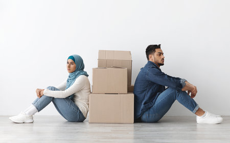 Upset arab family sitting separated by paper boxes on floorの写真素材