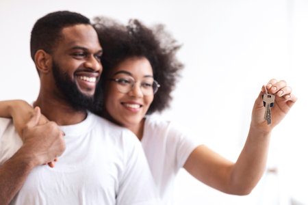 Happy African Couple Holding New House Key Hugging Standing Indoorの写真素材