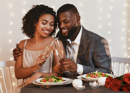 Romantic afro couple drinking champagne in fancy restaurantの写真素材