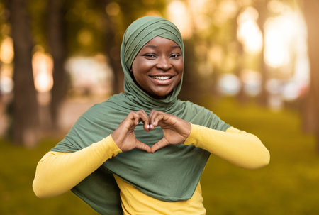 Love Concept. Smiling African Muslim Woman In Hijab Showing Heart Gestureの写真素材