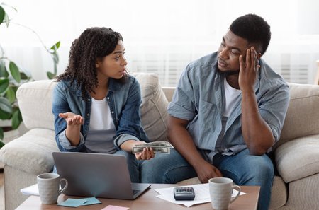 Couple accounting family budget at home, wife scolding husband for overspending