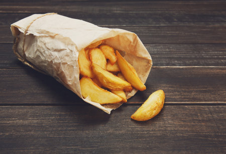 Tasty potato wedges wrapped for takeaway at woodの写真素材