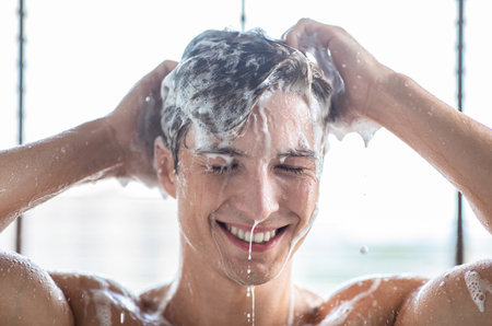 Handsome young male model washing hair with shampooの写真素材