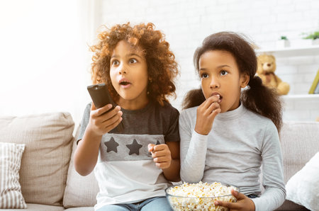 Little girls watching discovery channel and eating popcornの写真素材