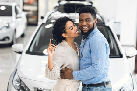 Couple Showing New Car Key Hugging Standing In Dealership Storeの写真素材