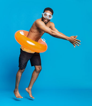Cheerful black shirtless man in swim goggles and inflatable ringの写真素材