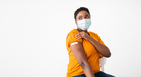 Vaccinated Black Woman Showing Arm With Adhesive Bandage, White Backgroundの写真素材