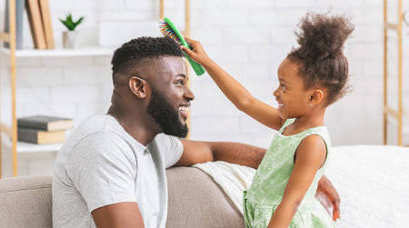 Young Girl Brushing Her Dads Hair While Sitting On Couchの写真素材