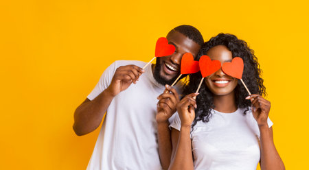 Young afro couple holding red love hearts over eyes