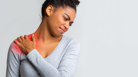 Sad girl having strong pain in shoulder, massaging painful zoneの写真素材