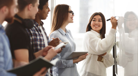 Students discussing tasks on whiteboard in classroomの写真素材