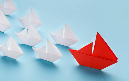 Red paper boat leading white ships, panoramaの写真素材