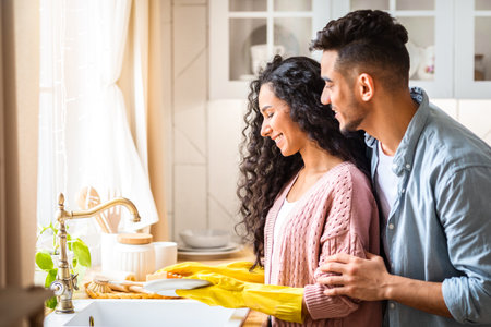 Portrait Of Happy Young Middle-Eastern Spouses Washing Dishes After Lunch In Kitchenの写真素材