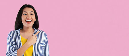 Smiling asian woman pointing aside at copy spaceの写真素材