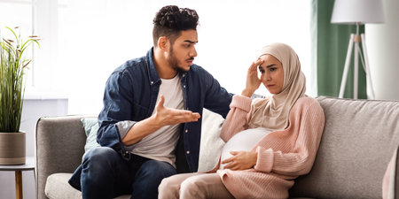 Agressive arab man arguing with his upset pregnant muslim wife at homeの写真素材