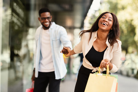 Excited Black Woman Pulling Boyfriend To Shopping Storeの写真素材