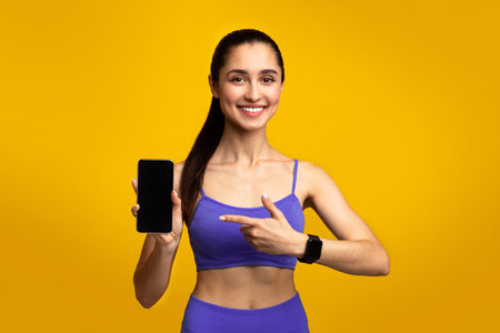Happy sporty woman showing phone with blank screenの写真素材